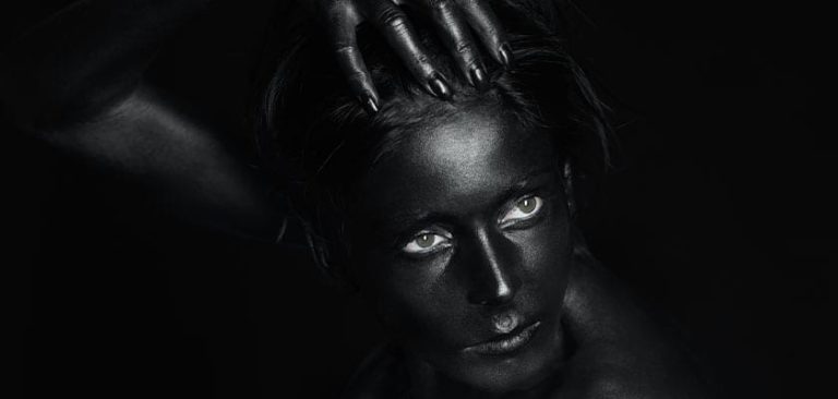 אישה בשחור מצולמת על רקע שחור משדרת את תחושת מועדון העין השחורה של האילומינטי